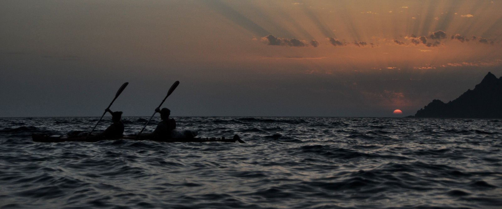 deux personnes sur un kayak biplace lors devant un coucher de soleil